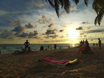 People on beach against sky during sunset
