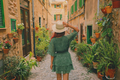 Woman in green dress, standing at charming street in the village of  valldemossa, mallorca