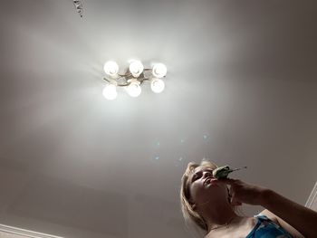 Low angle view of woman holding illuminated light against wall