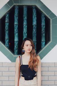 Young woman standing against wall