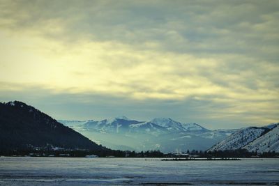 Scenic view of snow covered mountains against cloudy sky