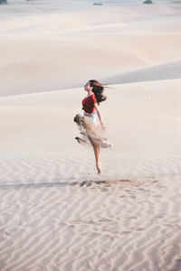 Woman dancing on sand at beach
