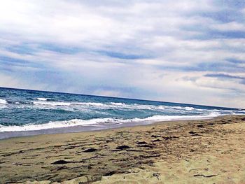Scenic view of beach against cloudy sky
