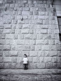 Full length of girl standing against wall