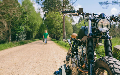 Motorcycle parked on footpath with man in background