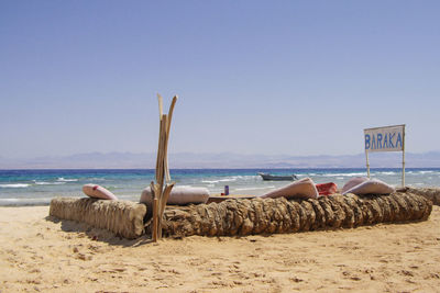 Lounge chairs on beach against clear sky