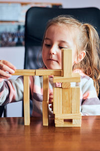 Little girl preschooler playing with wooden blocks toy building a tower. concept of building a house