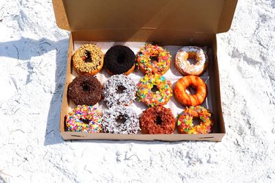 High angle view of donuts in box on sand