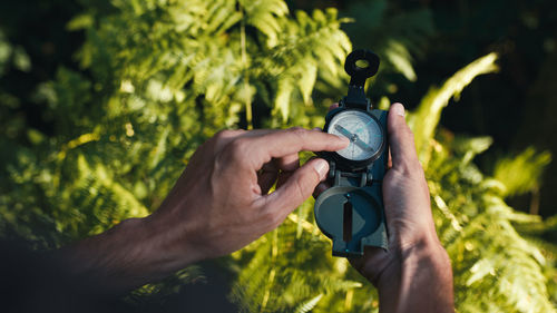 Hands of a boy opens the compass in the mountains to orient himself in the hike.