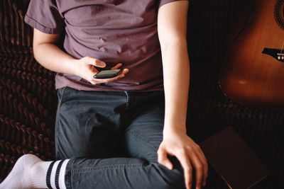 Teenage boy using smart phone while sitting on sofa at home