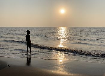 Full length of man on beach against sky during sunset