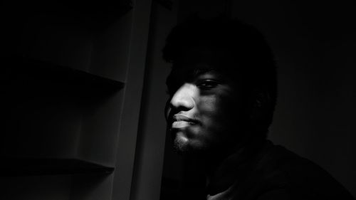 Close-up portrait of mid adult man against black background