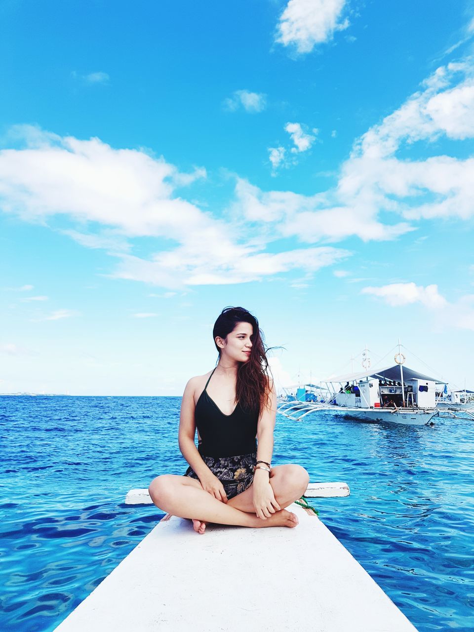 sky, water, sea, one person, sitting, cloud - sky, young adult, leisure activity, real people, outdoors, nature, young women, front view, lifestyles, day, beautiful woman, relaxation, beauty in nature, scenics, nautical vessel, vacations, horizon over water, adult, people