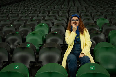 Confused woman sitting on chair at stadium