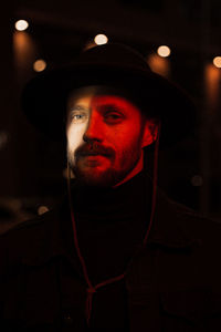 Portrait of man wearing hat at night