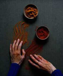 Top view of crop unrecognizable person touching table with spilled paprika and cinnamon powders