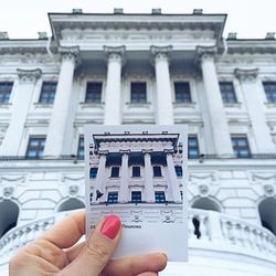 Cropped image of woman holding photograph by historic building