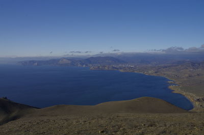 Scenic view of sea and mountains against blue sky