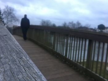 Man standing by railing against sky