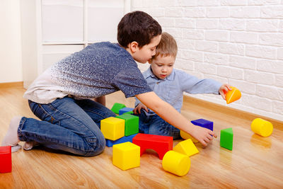 Beautiful children playing with constructor on floor at home