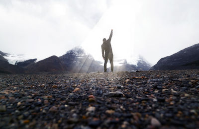 Rear view of man walking on mountain against sky