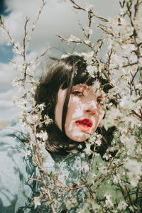 Close-up portrait of woman by plants against sky