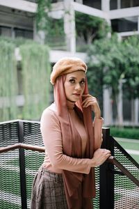 Portrait of woman standing against railing