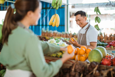 Rear view of woman holding fruits at market stall