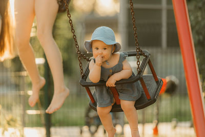 Portrait of young woman swinging at playground