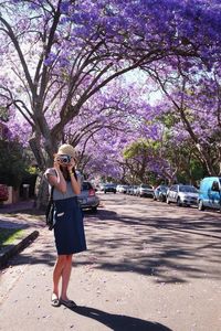 Full length of woman photographing with umbrella standing against trees