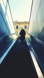 Rear view of silhouette woman on escalator against sky