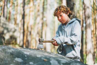 Boy looking at tree trunk in forest