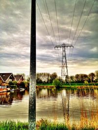 Electricity pylon against cloudy sky