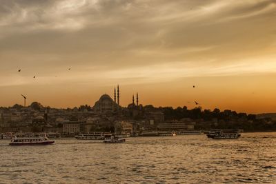 View of boats in river against cloudy sky