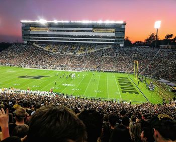 Crowd playing soccer on field at night