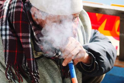 Close-up of man smoking hookah while sitting outdoors