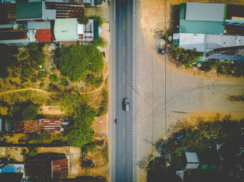 Road by trees in city against sky