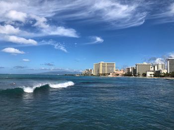 Sea by buildings against blue sky