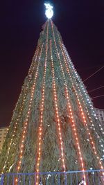 Low angle view of illuminated christmas tree against sky at night