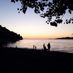 Silhouette of people on beach at sunset