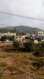 Houses on field by buildings against sky