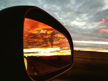 Reflection of orange sky on side-view mirror