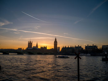 River and buildings against sky during sunset