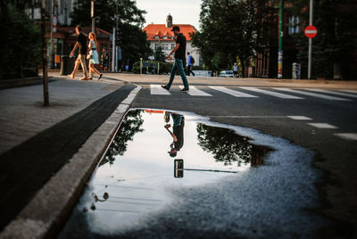 Reflection of man in puddle on street