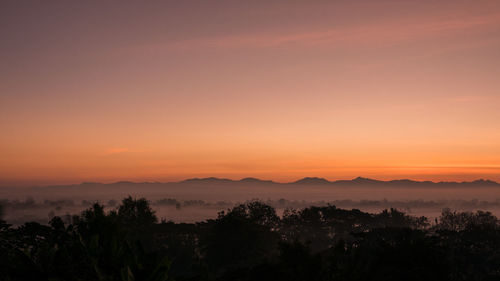 Scenic view of silhouette mountains against orange sky