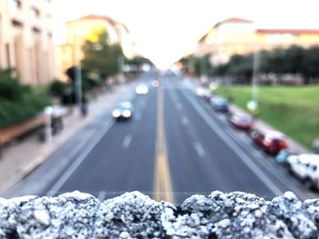 Snow on railing against road in city during sunset