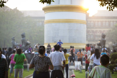 Rear view of people doing yoga in garden at morning