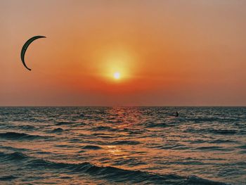 Scenic view of sea against sky during sunset with a silhouette of a wind surfer