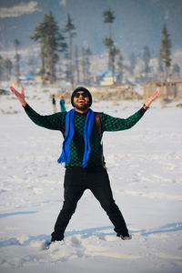 Full length portrait of smiling young man in snow