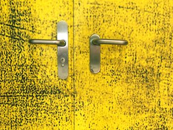 Close-up of yellow door with handles